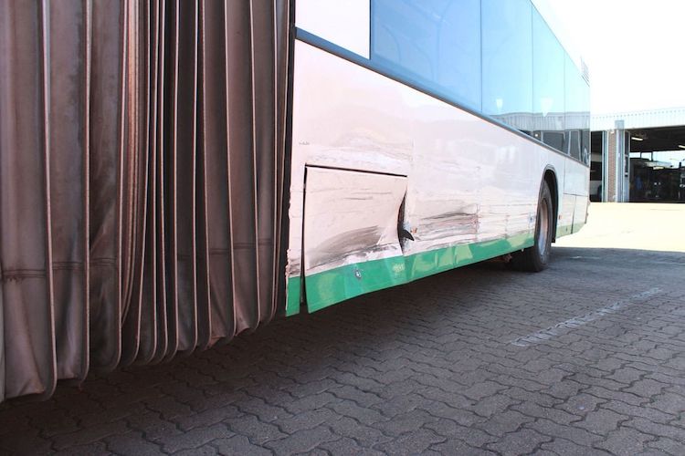 Beschädigter Bus nach einem Unfall auf dem Hof eines Unfallgutachters.